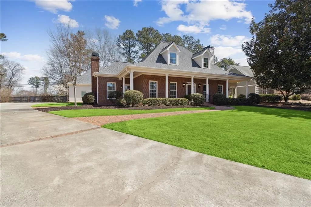 View of front facade with brick siding, concrete driveway, a chimney, and a front yard