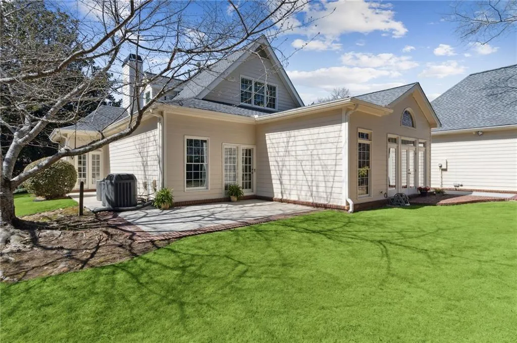 Rear view of house with a lawn, a patio, central AC, roof with shingles, and a chimney
