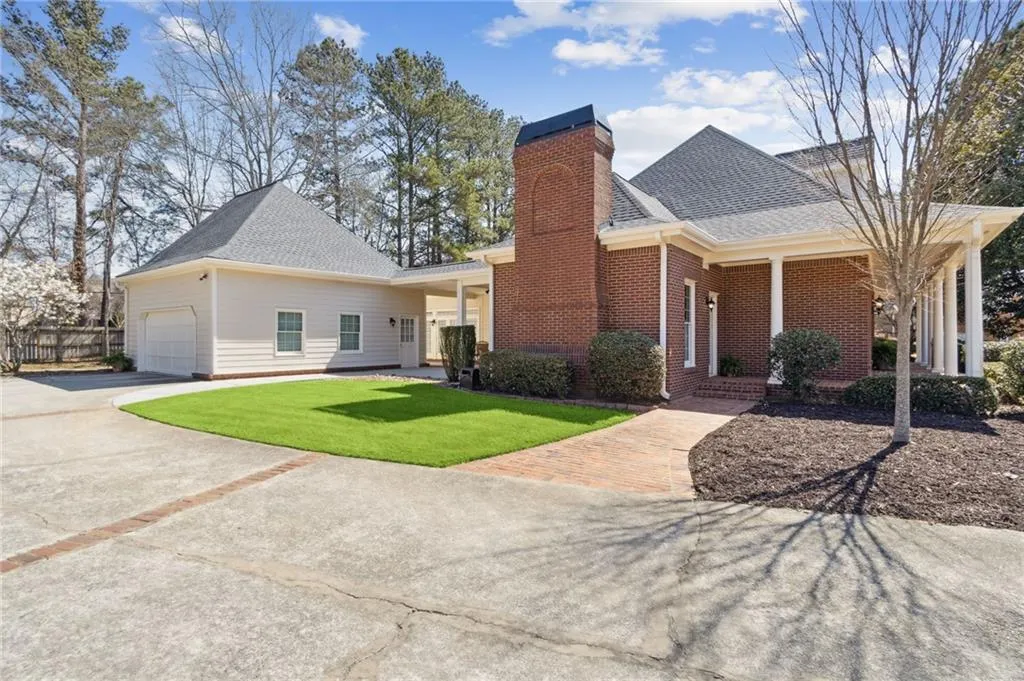 View of front facade with roof with shingles, an attached garage, concrete driveway, a front lawn, and brick siding