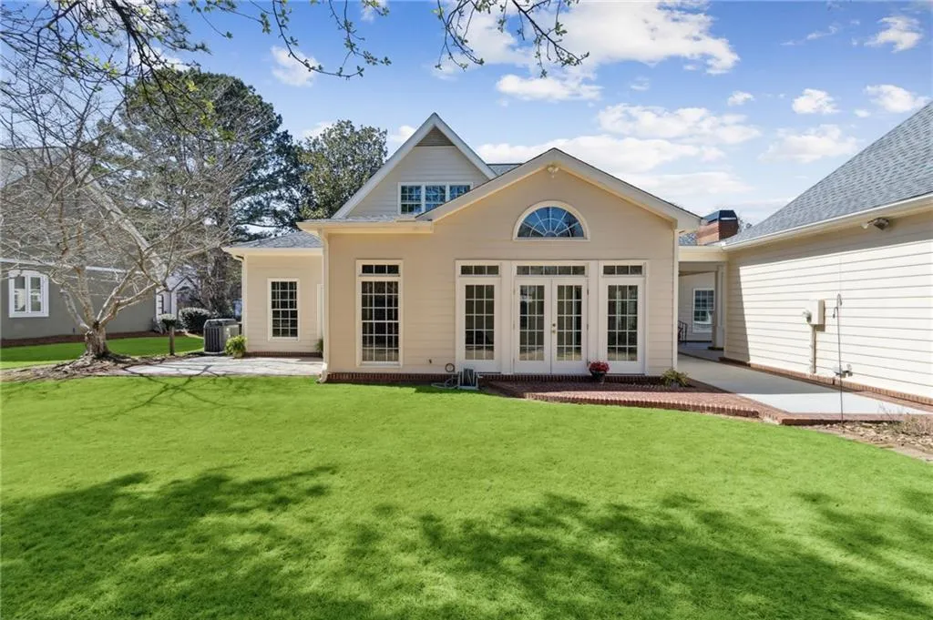 Back of property featuring french doors, a lawn, central AC unit, and a patio area