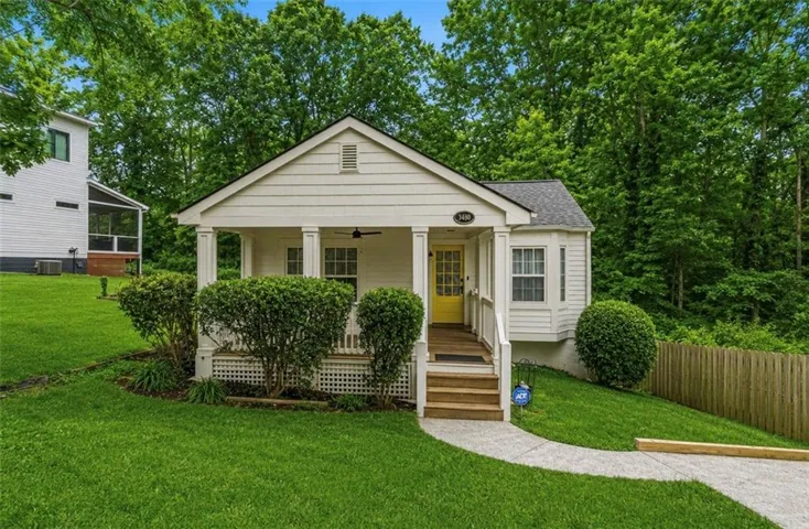 Cottage-style home featuring white siding, a covered porch with white columns, and a bright yellow front door