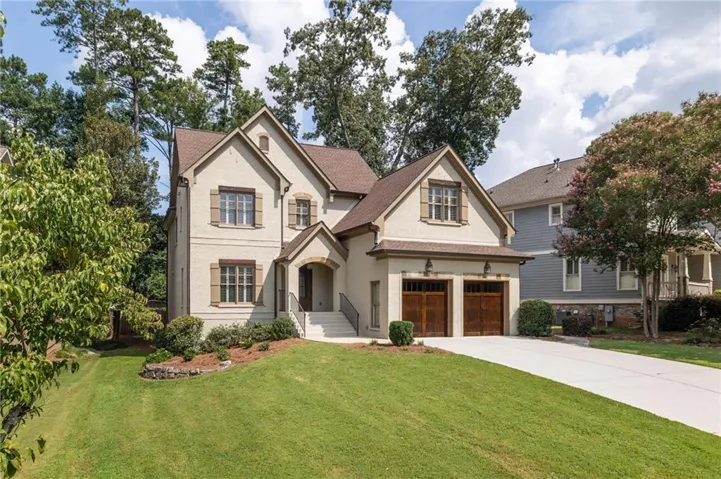4-sided brick estate with stone accents, covered entry, attached two-car garage with wood-finish doors, and a long concrete driveway with plenty of parking
