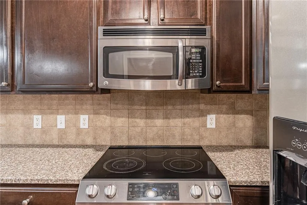 Kitchen featuring dark brown cabinets, stainless steel appliances, and decorative backsplash