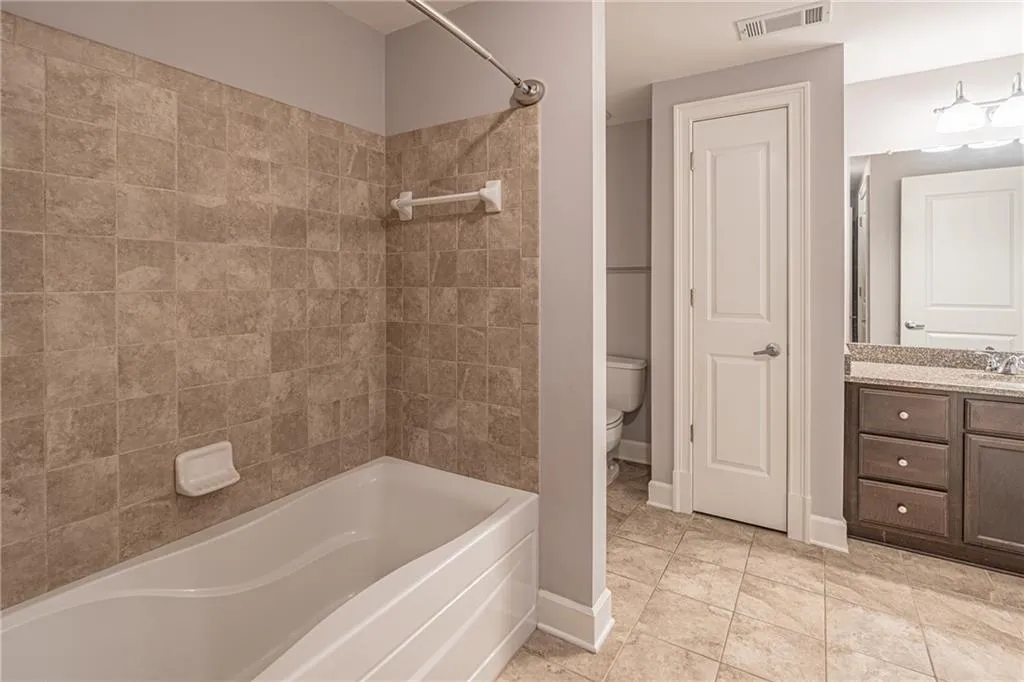 Full bathroom with bathing tub / shower combination, toilet, tile patterned floors, and vanity