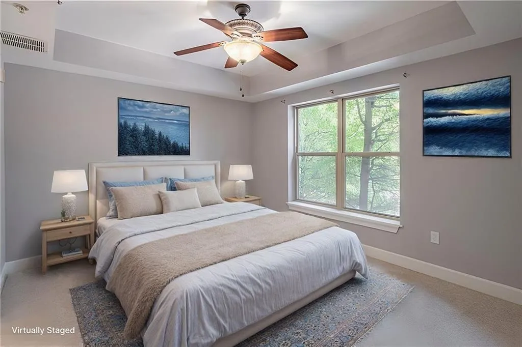 Carpeted bedroom with ceiling fan and a tray ceiling