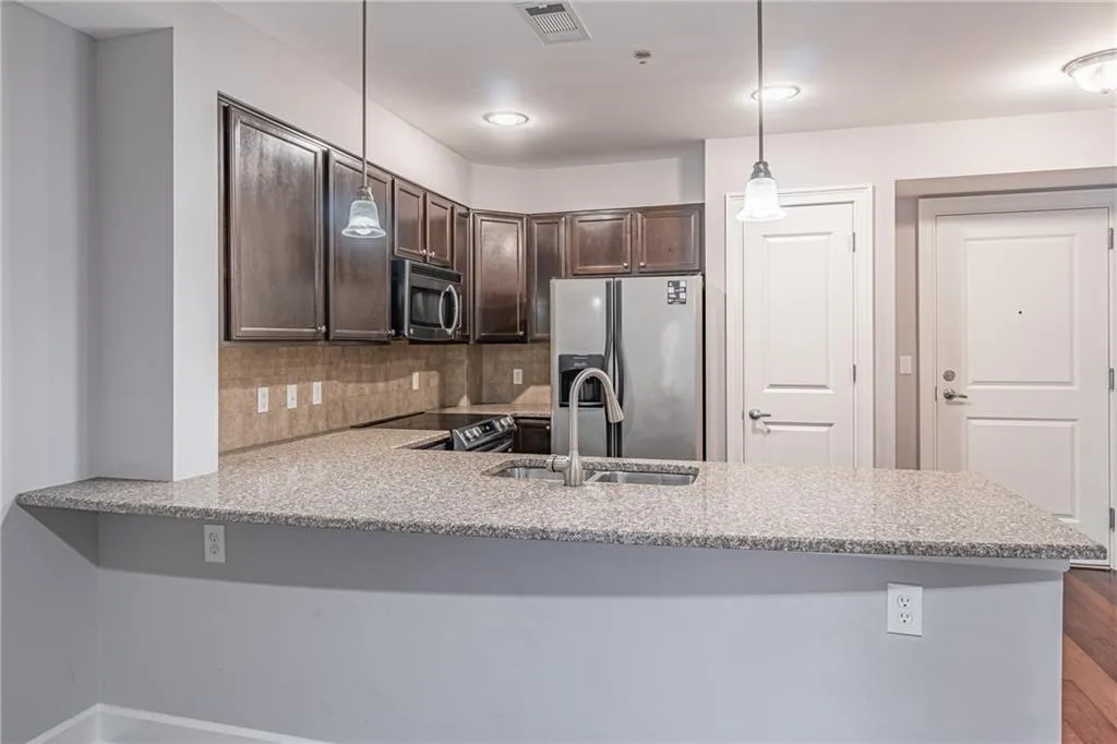 Kitchen featuring kitchen peninsula, pendant lighting, stainless steel appliances, and tasteful backsplash