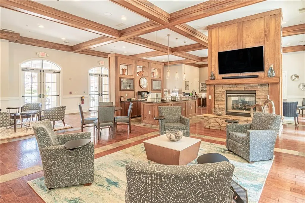 Living room with french doors, light wood-type flooring, beam ceiling, a stone fireplace, and coffered ceiling