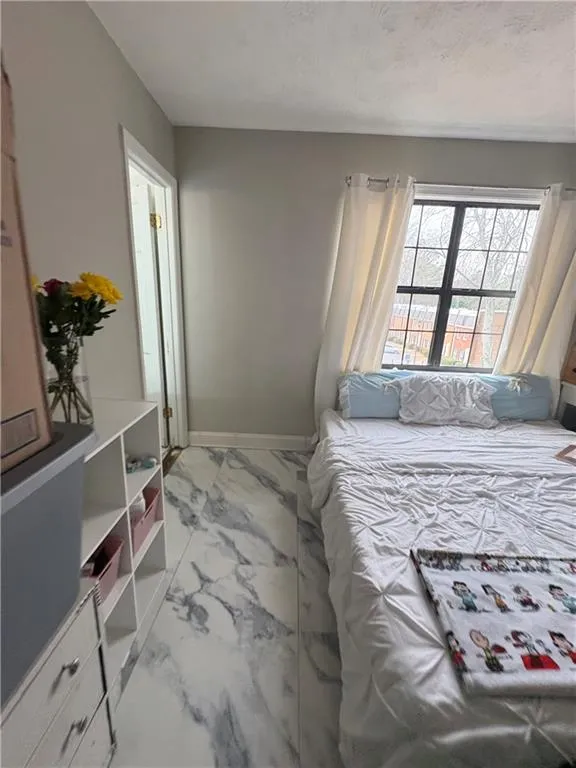 Bedroom with baseboards and light marble finish flooring