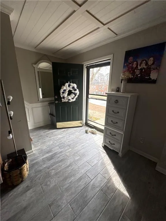Foyer featuring wood tiled floors, wooden ceiling, crown molding, and a decorative wall
