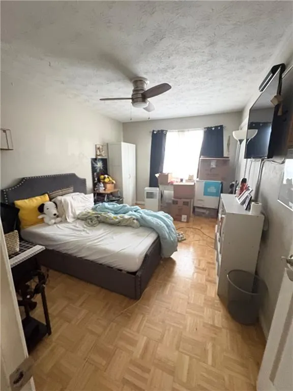 Bedroom featuring parquet floors, a ceiling fan, and a textured ceiling
