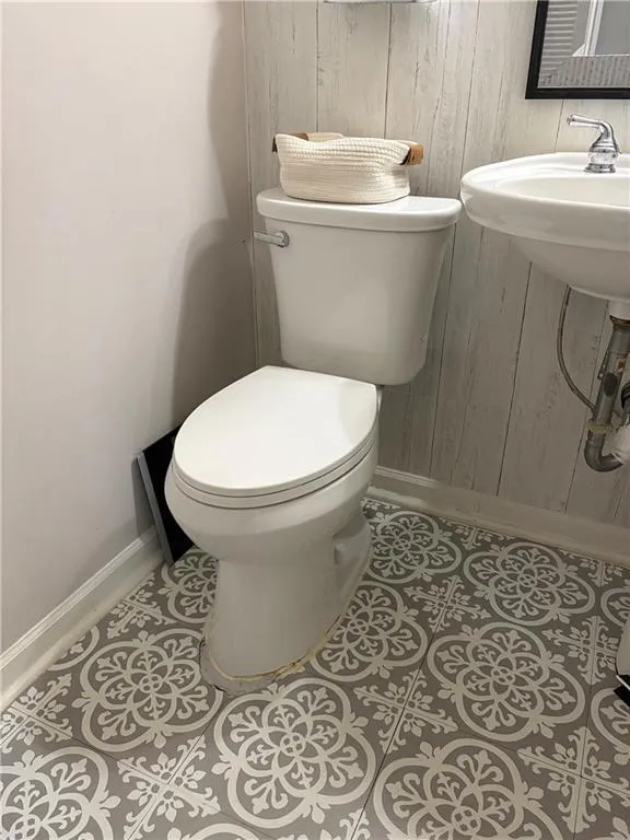 Half bath featuring light tile patterned floors and wooden walls