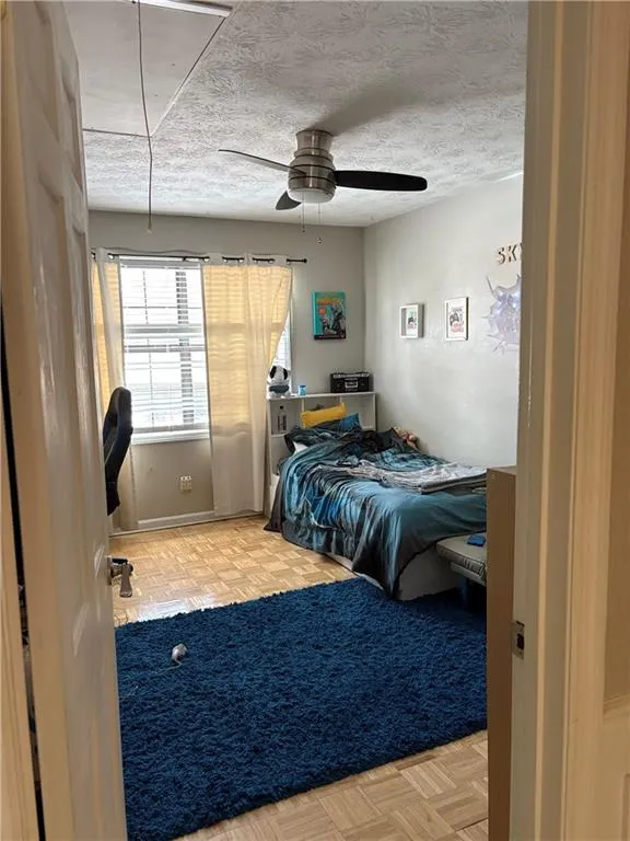 Bedroom featuring parquet floors, ceiling fan, a textured ceiling, and an office area