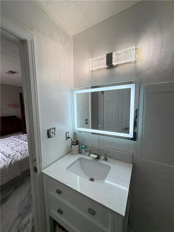 Bathroom featuring vanity, ensuite bathroom, and a textured ceiling