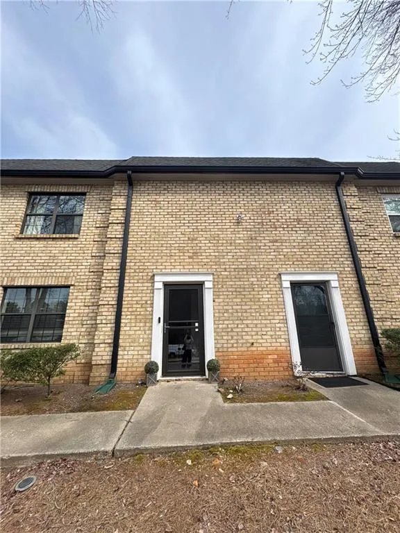 View of exterior entry featuring brick siding and a shingled roof