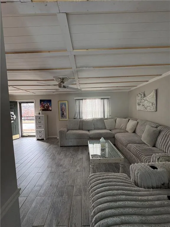 Living room with wood finished floors, beam ceiling, and a ceiling fan