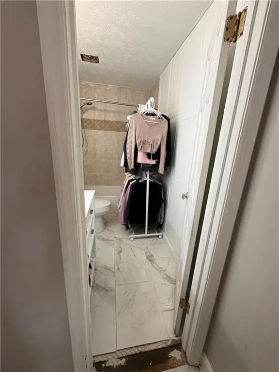 Full bathroom with vanity, light marble finish floors, a textured ceiling, and shower / washtub combination