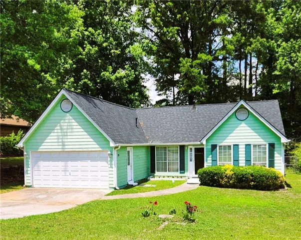 Mint green exterior siding with dark shutters, attached garage, and a manicured front lawn