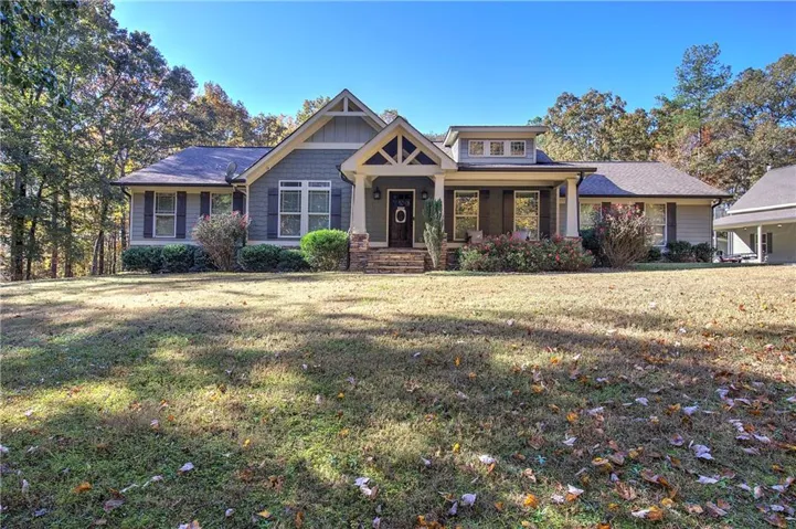 View of front of house with a porch, a front yard, and stone siding