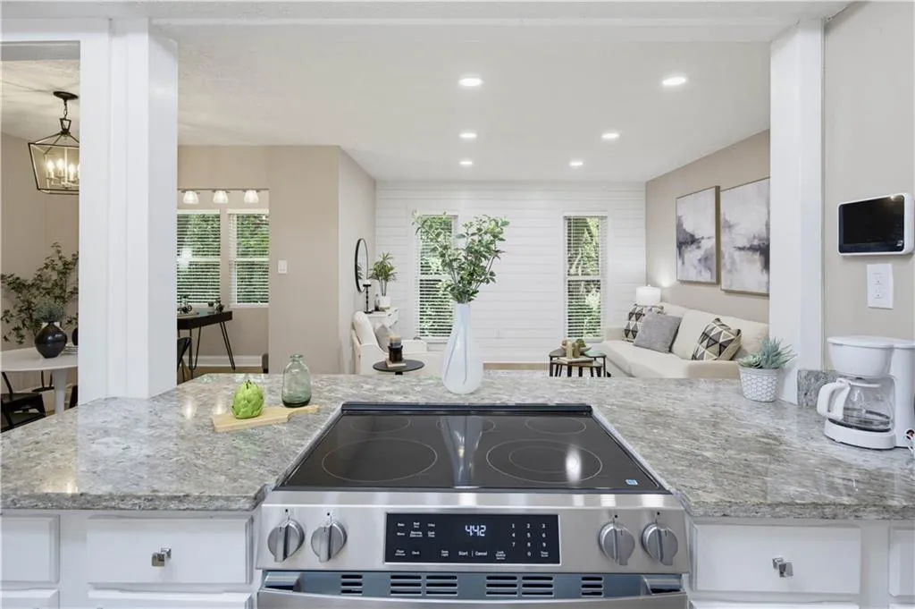Stainless steel range with a smooth cooktop, light-toned countertops, recessed ceiling lighting, and white cabinetry
