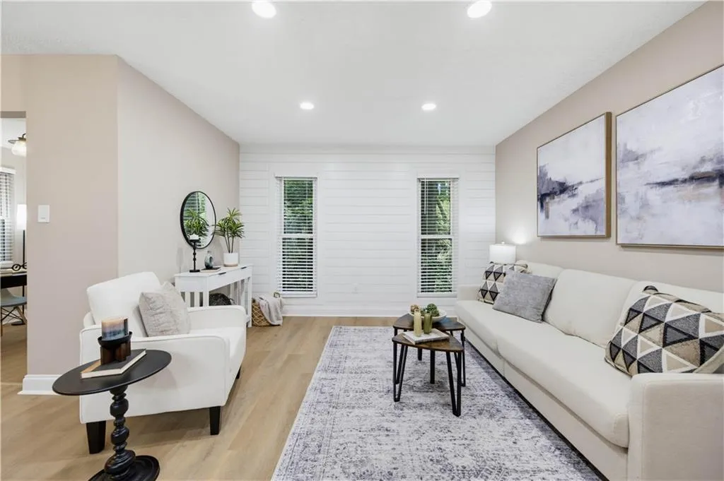 Recessed lighting illuminates an interior with light-toned walls and wood-finish flooring
