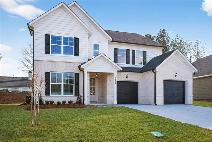 Traditional home featuring a front yard, driveway, brick siding, and a shingled roof