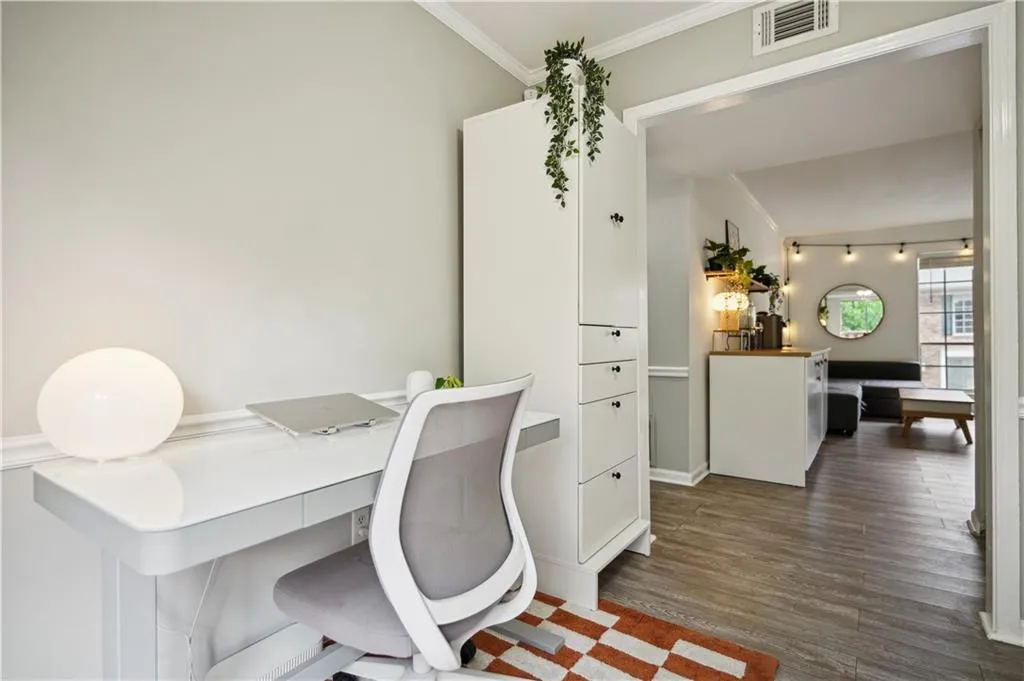 Office space with dark hardwood / wood-style flooring and crown molding