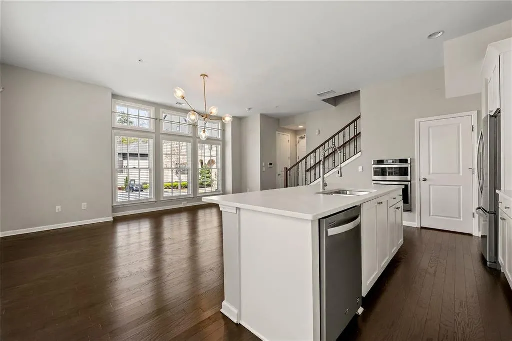 Kitchen with open floor plan, an inviting chandelier, a sink, dark wood-style floors, and appliances with stainless steel finishes