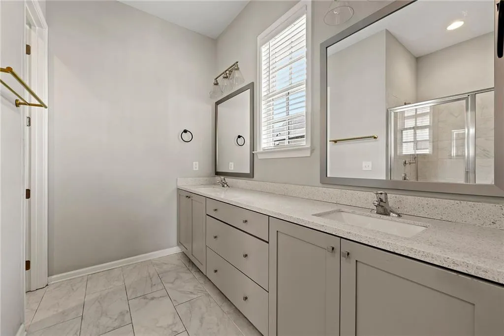 Bathroom featuring marble finish floor, a sink, double vanity, and a shower stall