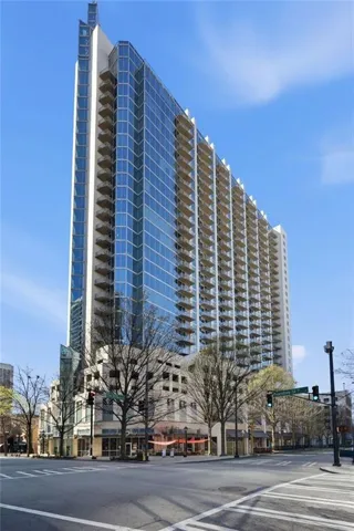 Modern high-rise residential building featuring a glass facade and numerous private balconies