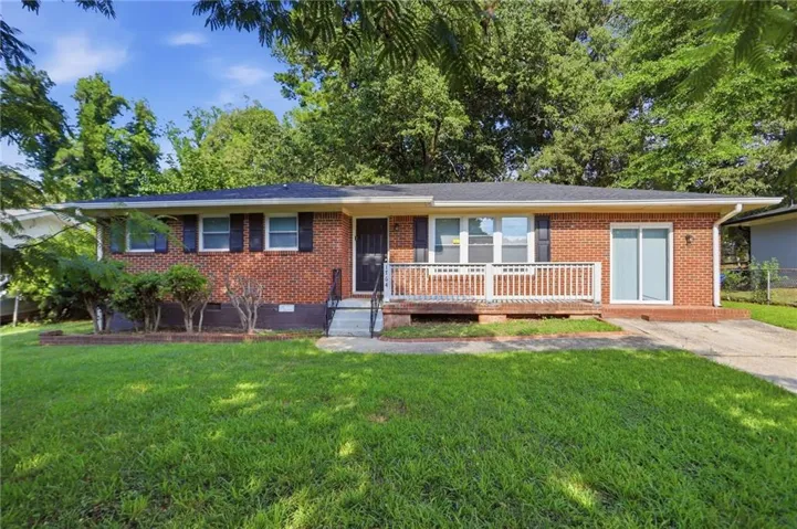Brick facade home featuring a front porch with white railing, a dark entry door, and a sliding glass door