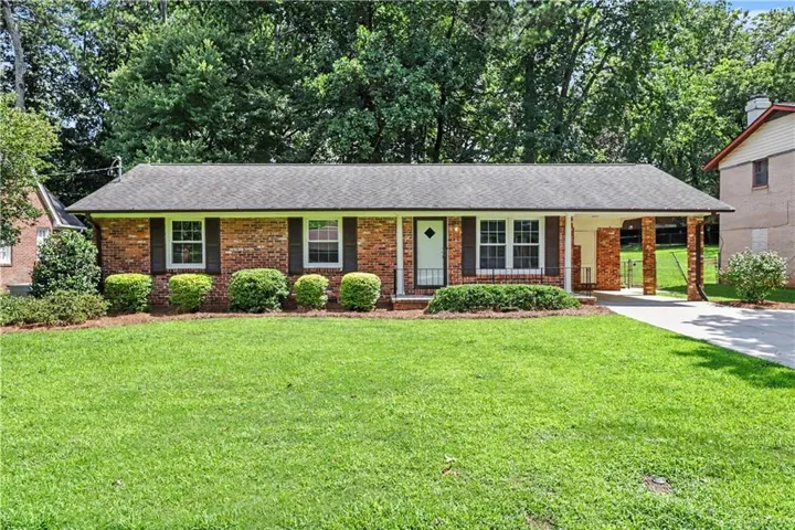 Brick ranch-style residence featuring a charcoal shingle roof and a covered carport with brick columns