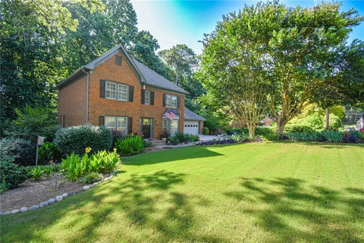 Brick exterior residence with a two-car garage, featuring a gabled roofline and dark window shutters