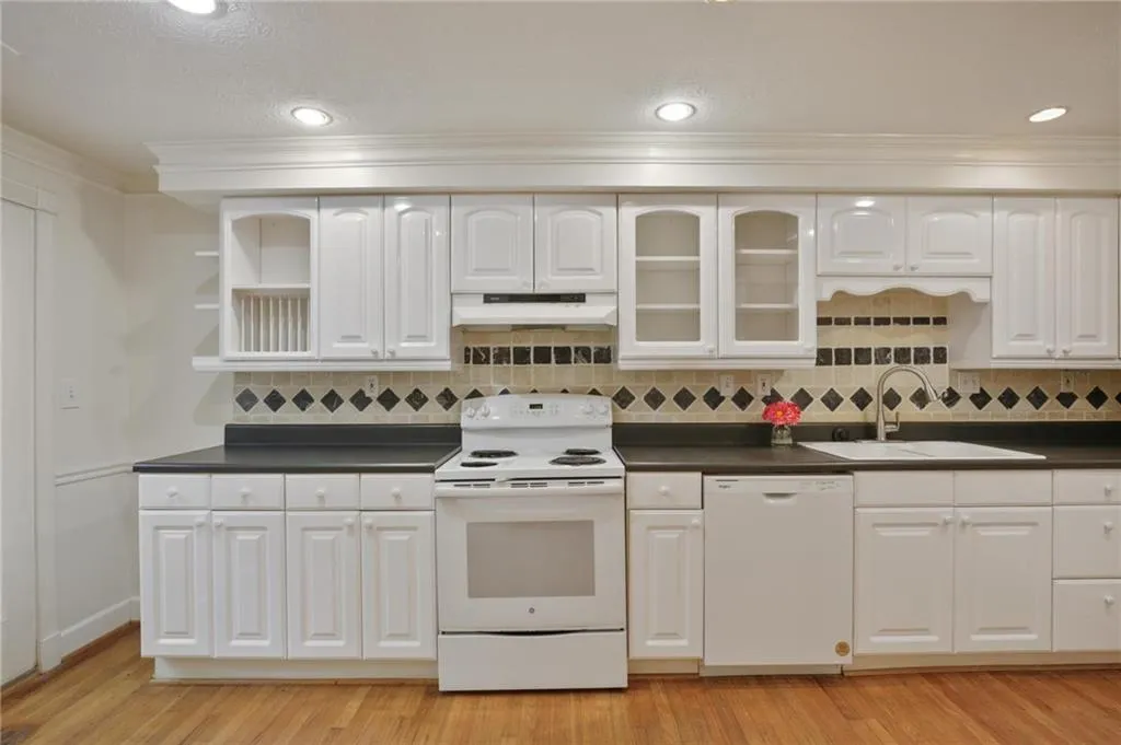 Kitchen featuring white appliances, sink, white cabinets, and light wood-type flooring