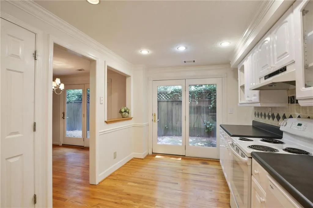 Kitchen featuring crown molding, light hardwood / wood-style flooring, white cabinets, and white appliances