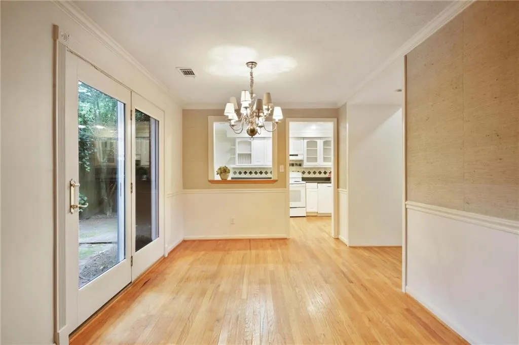 Unfurnished dining area featuring a notable chandelier, ornamental molding, and light wood-type flooring