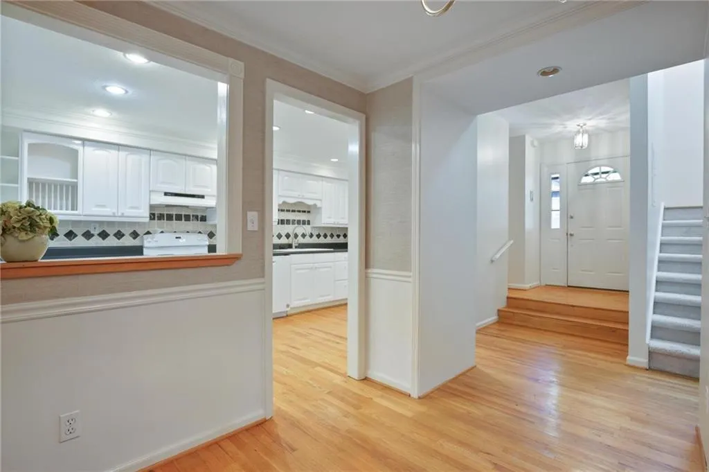 Kitchen with light hardwood / wood-style floors, stove, custom range hood, backsplash, and white cabinetry