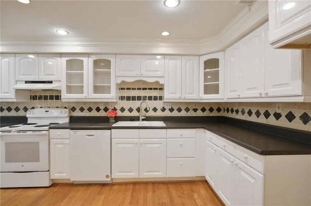 Kitchen featuring white cabinets, sink, white appliances, and light hardwood / wood-style flooring
