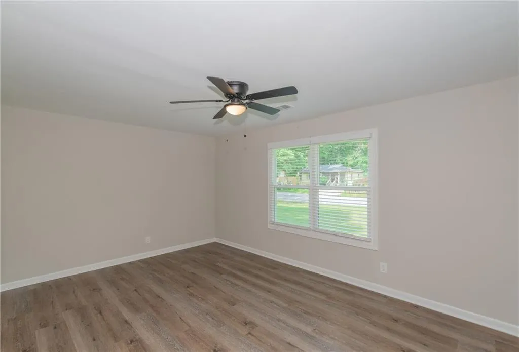 Unfurnished room with dark wood-style floors, plenty of natural light, a textured ceiling, baseboards, and a smoke detector