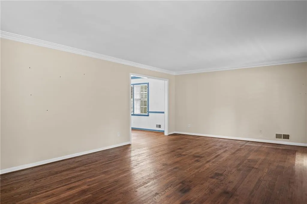 Empty room with dark wood-style floors and ornamental molding