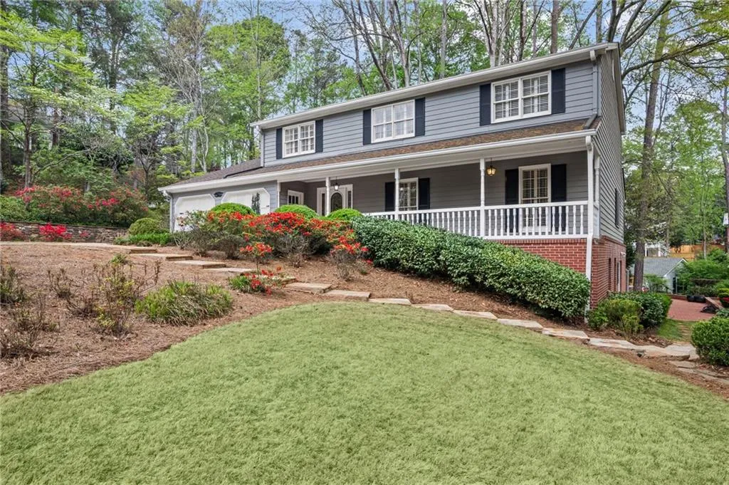 View of front of property with a porch, an attached garage, a front lawn, and brick siding