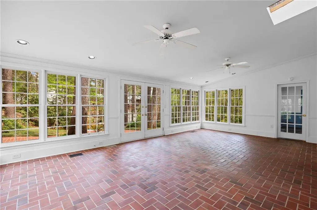 Unfurnished sunroom featuring french doors, brick flooring, crown molding, recessed lighting, and lofted ceiling