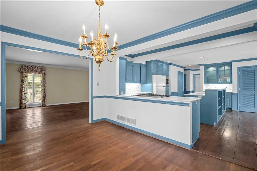 Kitchen featuring blue cabinetry, glass fronted cabinets, light countertops, hanging lights, and crown molding
