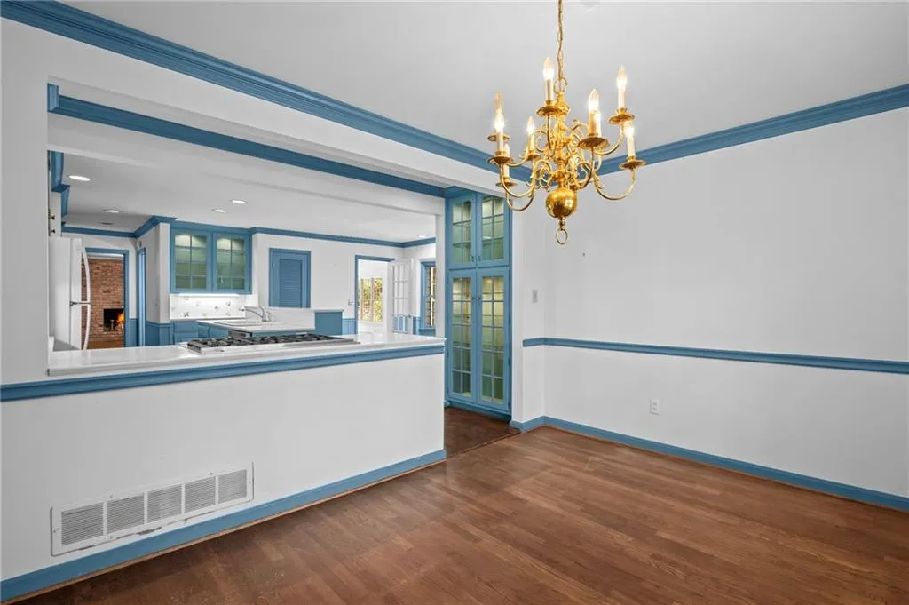 Unfurnished dining area with a chandelier, dark wood-style floors, and crown molding