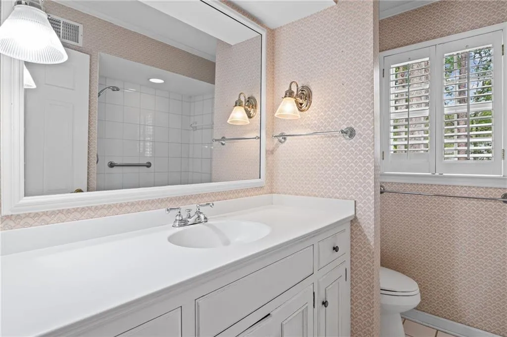 Full bathroom featuring wallpapered walls, vanity, a shower, crown molding, and light tile patterned floors