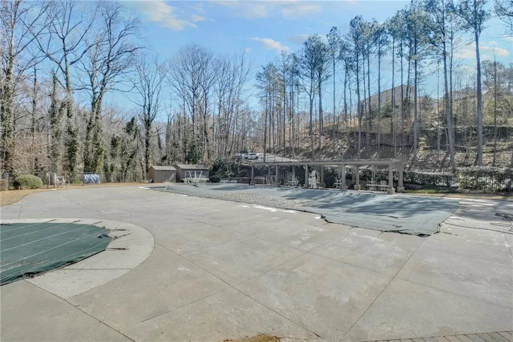 View of swimming pool featuring a covered pool and view of scattered trees