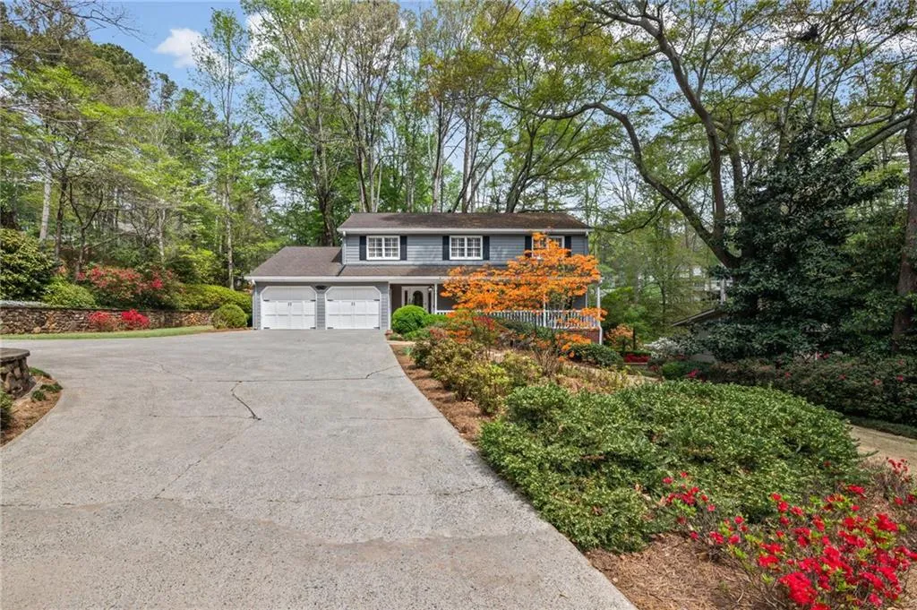 Traditional-style home with driveway, an attached garage, and view of scattered trees