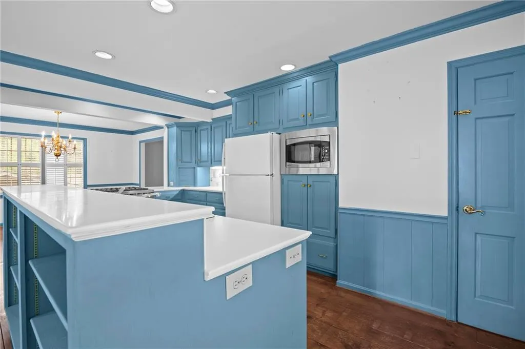Kitchen featuring blue cabinetry, open shelves, stainless steel appliances, light countertops, and dark wood-style floors