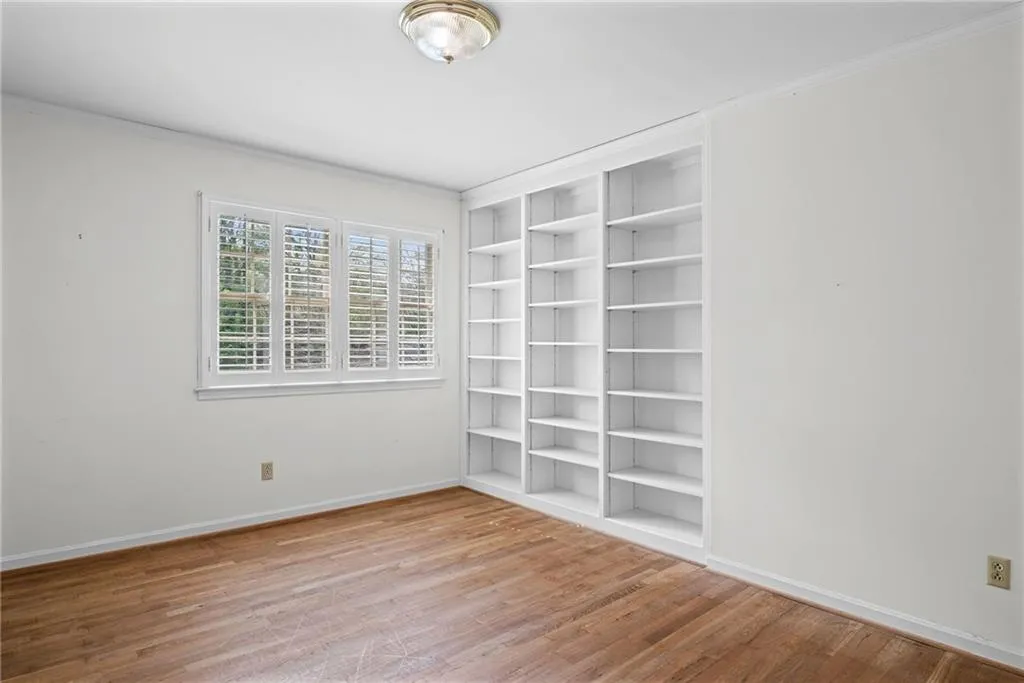 Spare room featuring built in features, light wood-type flooring, and crown molding