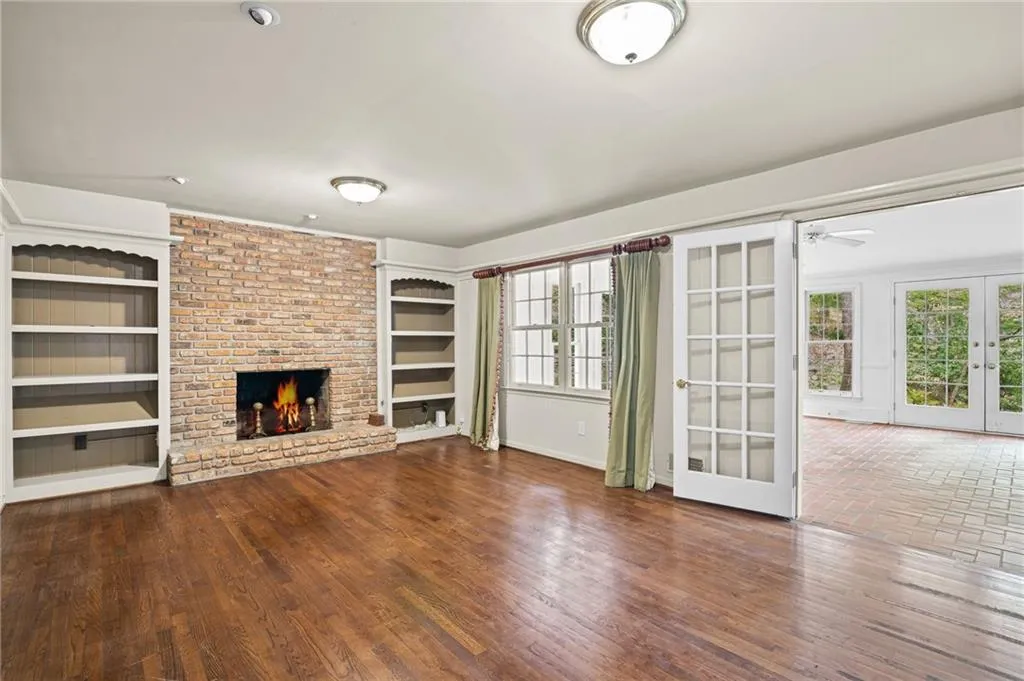 Unfurnished living room with french doors, a fireplace, dark wood-type flooring, and a ceiling fan