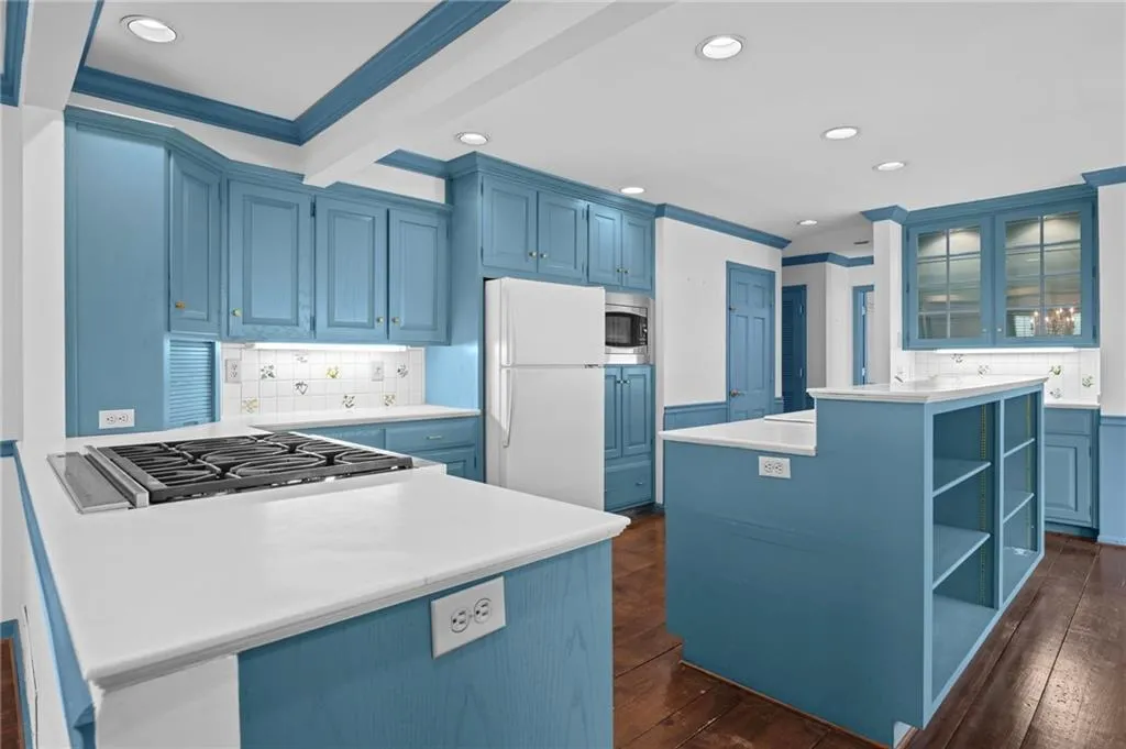 Kitchen featuring blue cabinetry, open shelves, tasteful backsplash, a center island, and crown molding